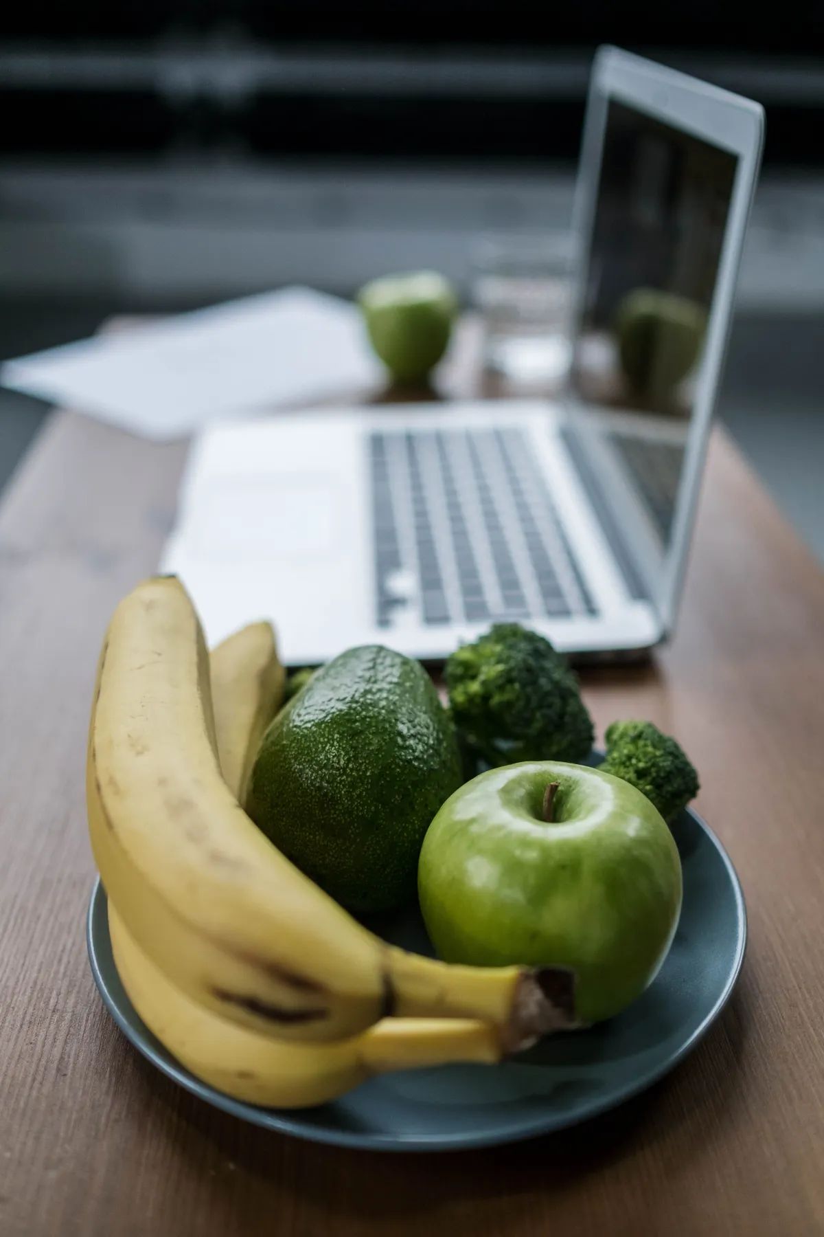 Fruta e vegetais frescos junto a um computador portátil, num espaço de trabalho